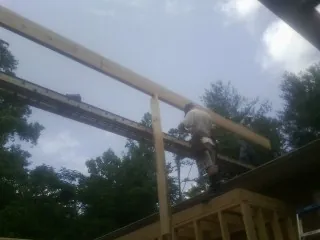 Carpenter setting a ridge beam over a new addition frame — Ice Dam Removal by Roofing Brothers in Monticello