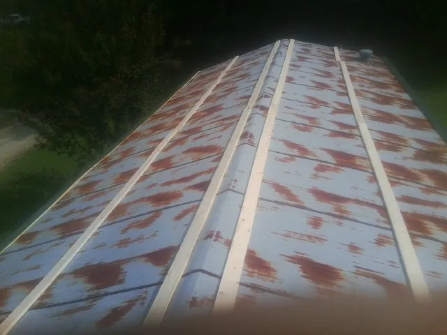Rusted metal roof panels with new wood purlins before replacement in Monticello